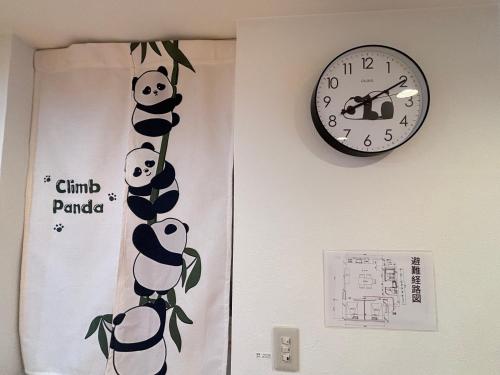 a clock on a wall next to a door with pandas on it at 晴の浜 in Wakayama