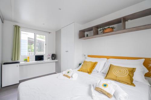 a white bedroom with a large white bed with yellow pillows at Club del Sole Vigna sul Mar Family Collection in Lido di Pomposa