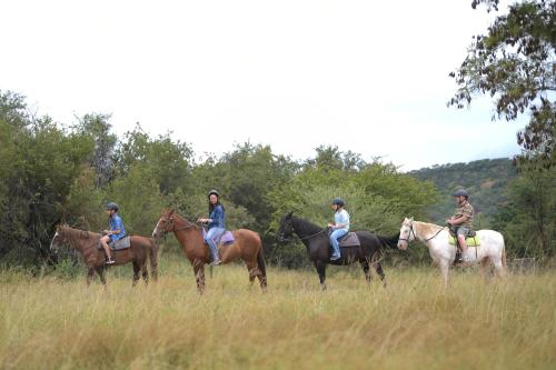 a group of people riding horses in a field at ATKV Klein-Kariba in Bela-Bela