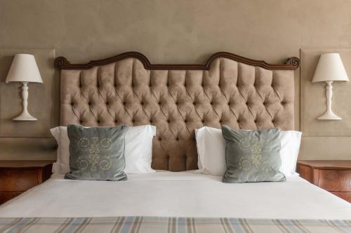 a large bed with a large headboard and pillows at Grand Hotel Fasano in Gardone Riviera