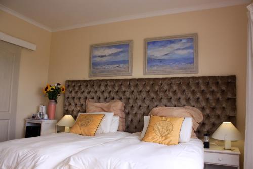 a bedroom with a large bed and two pictures on the wall at Blougans B&B in Gansbaai