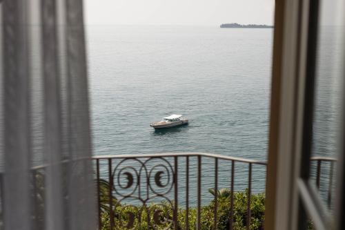 a small boat in the water from a balcony at Grand Hotel Fasano in Gardone Riviera