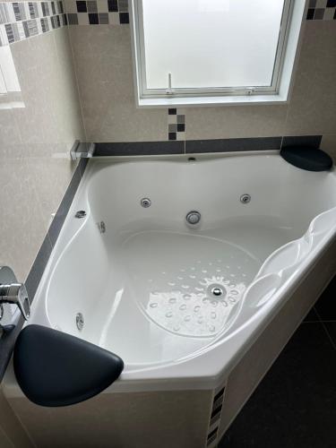 a white bath tub with a chair in a bathroom at Hamilton Cozy Corner Retreat in Hamilton