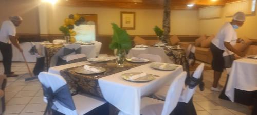 a restaurant with white tables and chairs and two people at THOKOZA ANGLICAN CONFERENCE CENTRE in Mbabane