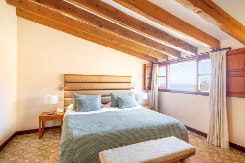 a bedroom with a large bed and a window at Hotel y Apartamentos DES PUIG in Deia