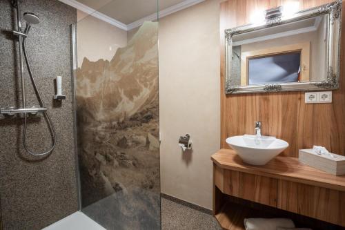 a bathroom with a sink and a shower with a mirror at Pension Edelweiss in Breitenbach