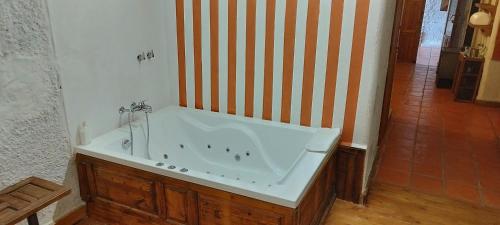 a bath tub in a bathroom with a striped wall at Casas Cueva y Cortijo La Tala en Guadix in Guadix