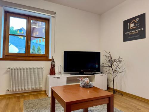 a living room with a tv and a coffee table at Mountain Space Tarvisio in Tarvisio