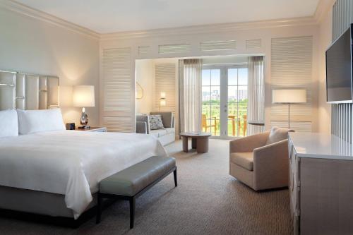 a hotel room with a large bed and a chair at JW Marriott Miami Turnberry Resort & Spa in Aventura