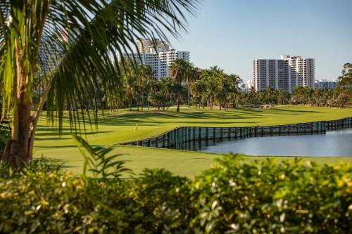 a golf course with a pond and palm trees and buildings at JW Marriott Miami Turnberry Resort & Spa in Aventura