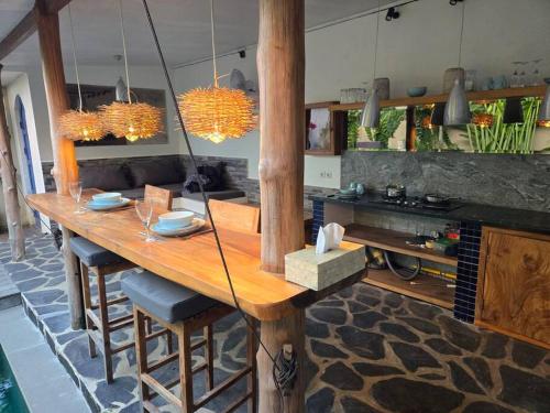 a kitchen with a wooden table with chairs and lights at Villa crush of heart with swimming pool in Umalas