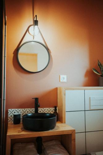 a bathroom with a black sink and a mirror at Aux Trois Chênes Lodges Spas in Mercuès