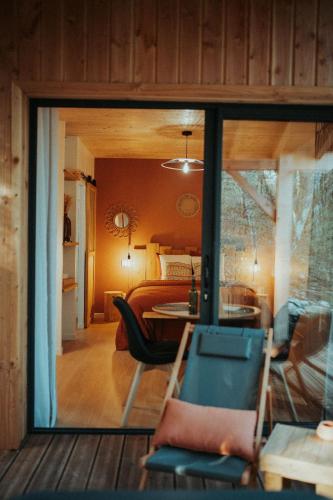 a room with a view of a bedroom and a living room at Aux Trois Chênes Lodges Spas in Mercuès