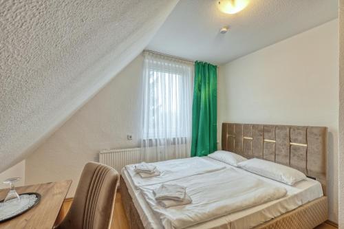 a bedroom with a bed and a table and a green curtain at Werrapark Resort Hotel Frankenblick in Masserberg