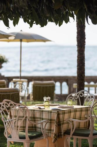 a table with chairs and an umbrella and the ocean at Grand Hotel Fasano in Gardone Riviera