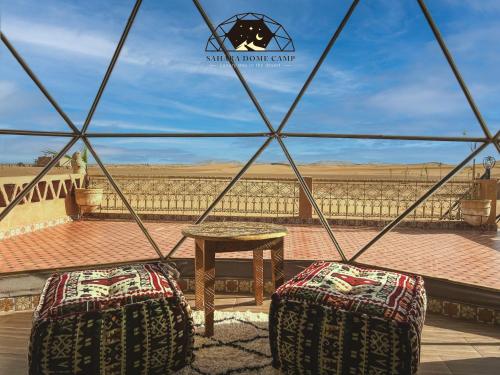 a view from inside a tent with two chairs and a table at Royal Sahara Dome Camp in Merzouga