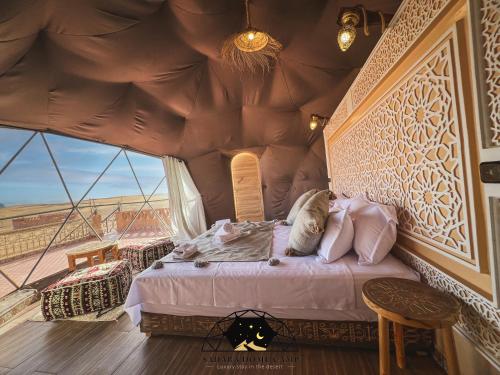 a bed in a room with a large window at Royal Sahara Dome Camp in Merzouga