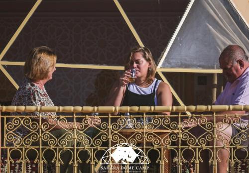 two women and a man are standing behind a fence at Royal Sahara Dome Camp in Merzouga