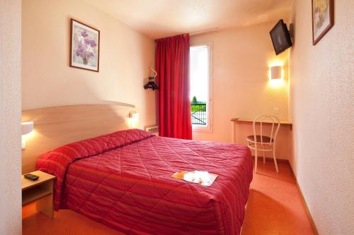 a hotel room with a red bed and a window at Premiere Classe Dreux in Dreux