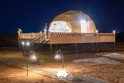 a dome tent with lights in front of it at night at Royal Sahara Dome Camp in Merzouga
