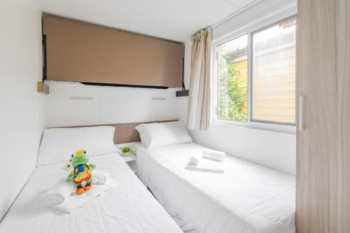 a bedroom with two beds and a teddy bear sitting between them at Club del Sole Vigna sul Mar Family Collection in Lido di Pomposa