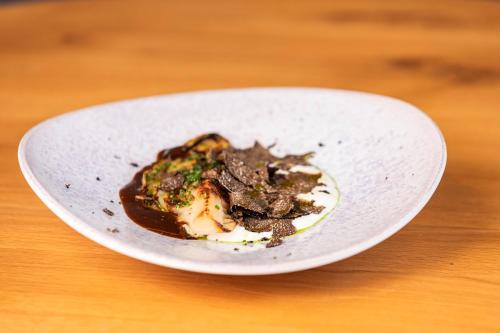 a white plate of food on a wooden table at Ca' Bonfadini Historic Experience in Venice
