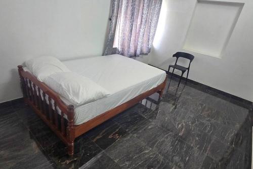 a bed in a room with a window and a chair at Entire 4 Bedroom Villa in Kannur in Edakkād