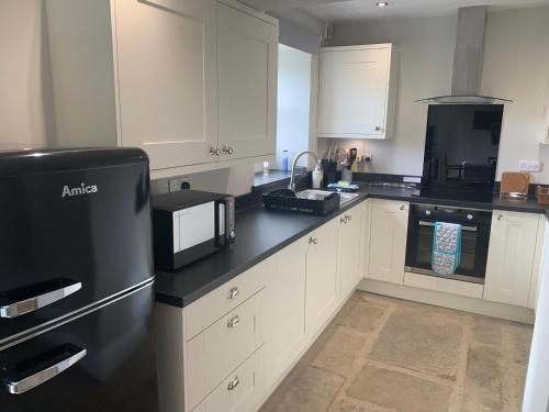a kitchen with white cabinets and a black refrigerator at White Lea in Grinton