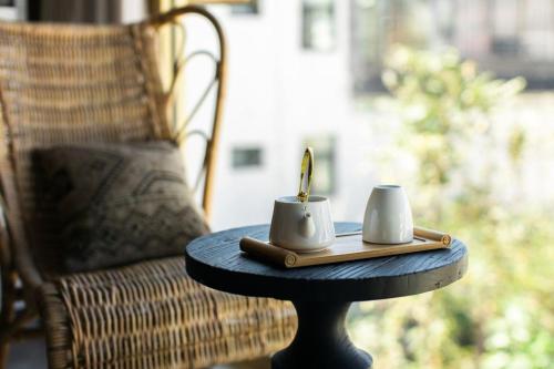 a table with two mugs and a candle on it at Dali Wuwei Puruohaijing Hotel大理无为普若海景酒店 in Dali