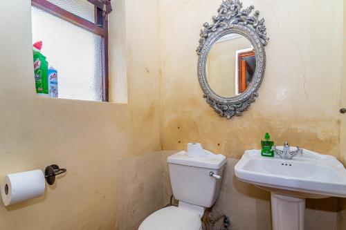 a bathroom with a toilet and a sink and a mirror at Queensview in De Kelders