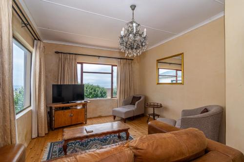 a living room with a couch and a tv at Queensview in De Kelders