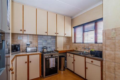 a kitchen with white cabinets and a stove top oven at Queensview in De Kelders