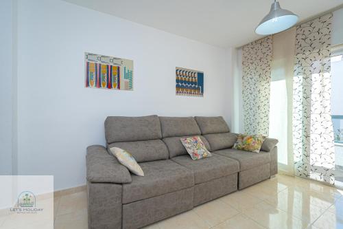 ein Wohnzimmer mit einer braunen Couch in einem Zimmer in der Unterkunft Bonito apartamento cerca de playa in El Campello