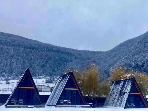 two triangular structures in the snow with mountains in the background at Kvabtkari Cottages in Ambrolauri