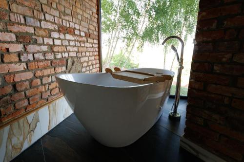 a white bath tub in a room with a brick wall at Vdoma Karpaty in Vilshynki