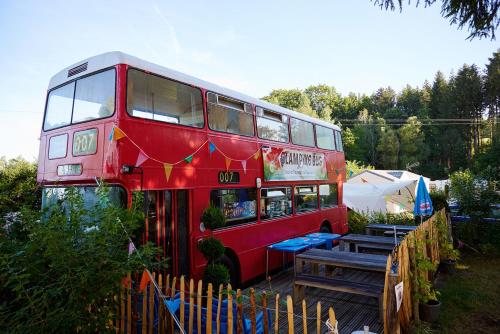 un bus rouge à deux étages garé dans une cour dans l'établissement Glamping the Vosges, à Corcieux