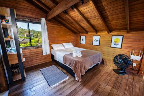 a bedroom with a bed in a wooden room at Cabana Perfeita a 800m da Praia - Lareira externa, Quintal Amplo, Pet Friendly, Ar condicionado, Netflix e Conforto completo in Imbituba