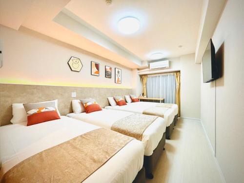 a hotel room with three beds and a television at Hotel Arashi Nambaminami No003 in Osaka