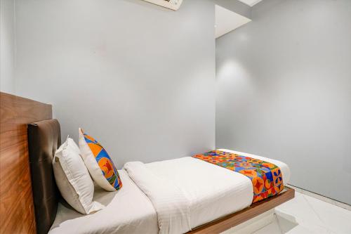 a small white room with a bed and some pillows at FabExpress Powai Inn in Mumbai