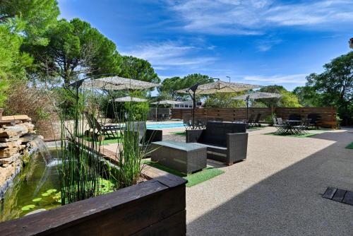 une terrasse avec un étang, un banc et une table dans l'établissement Villa Martégale Hôtel Restaurant, à Martigues