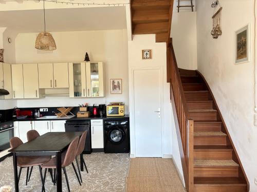 une cuisine avec une table à manger et un escalier dans l'établissement Les Douves Duplex 5 personnes lumineux avec jardin et terrasse aménagée , vue sur château à 5mn de la mer, proche Omaha Beach et Bayeux, à Commes