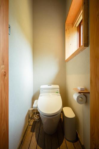 a bathroom with a white toilet in a room at 大山初里 Origin Villa Village Hotel&Resort in Tonglu