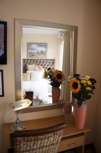 a mirror reflecting a bedroom with a bed and flowers at Blougans B&B in Gansbaai