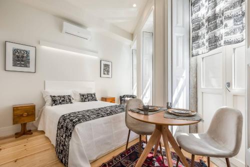 a white bedroom with a bed and a table and chairs at Beco do Paço by Porto Dream Stays in Porto