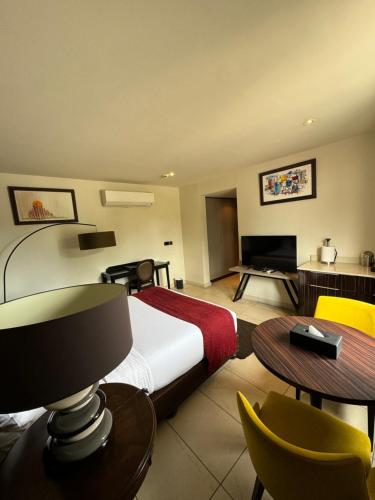 a hotel room with a bed and a table and chairs at The Palms by Eagles Accra in Accra