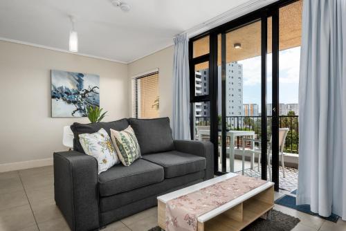 a living room with a couch and a balcony at Waters Edge Apartments in Cape Town
