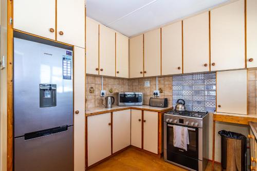 a kitchen with white cabinets and a refrigerator at Queensview in De Kelders