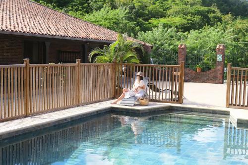 a woman sitting in a chair next to a swimming pool at Domaine du Château in Les Trois-Îlets