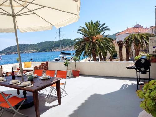 a patio with a table with chairs and an umbrella at Waterfront House Carolina in Vis