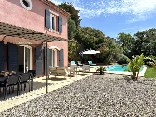 un patio avec des chaises et un parasol à côté d'une piscine dans l'établissement Villa Paloma pour 6 personnes avec piscine privée, à deux pas du Golf de Valcros, à La Londe-Les-Maures, à La Londe-les-Maures